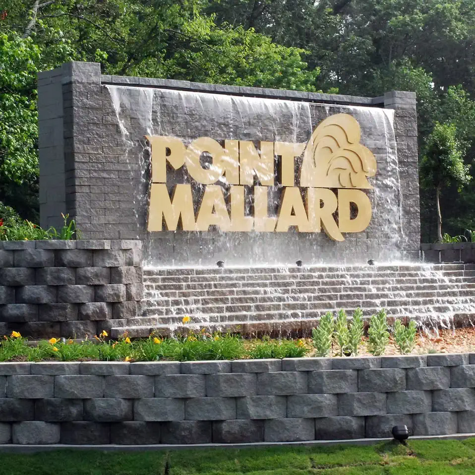 The Point Mallard entrance sign set into a stone waterfall feature.